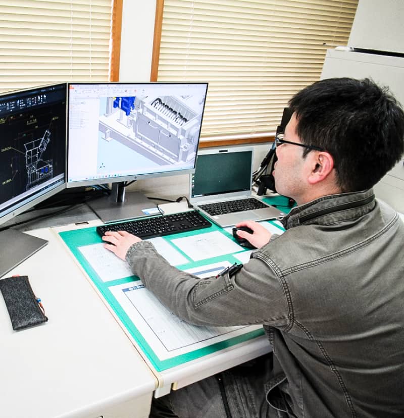 男性がCADソフトウェアを使用して機械部品の3Dモデルを設計しているオフィスの作業環境